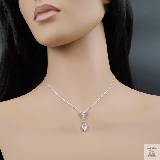 Mannequin wearing a silver necklace with a teardrop pendant on a dark background