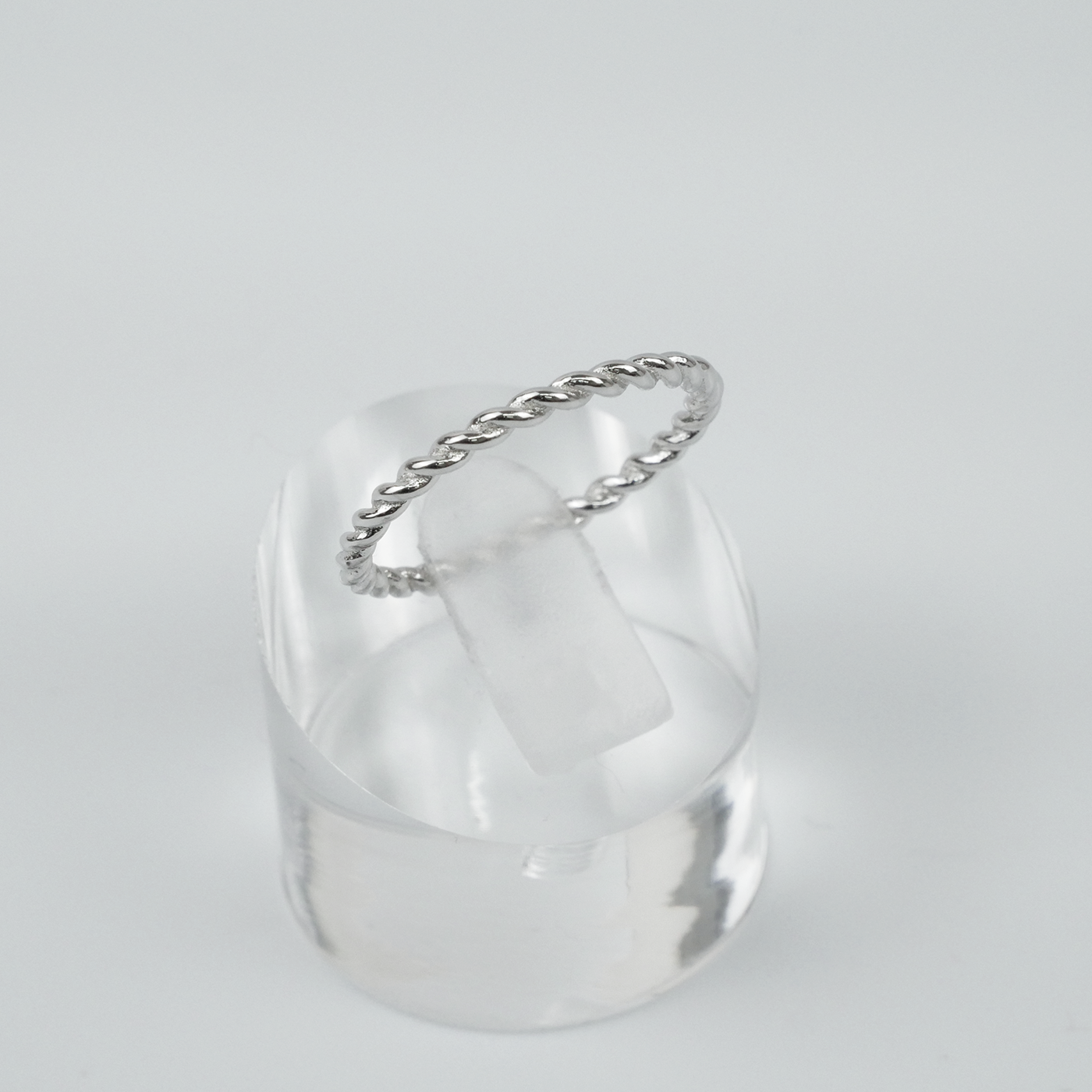 Silver ring with a twist design on a light grey background