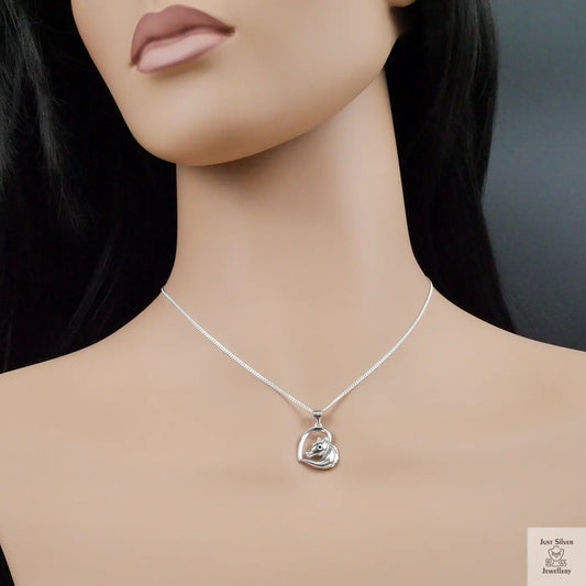 Mannequin wearing a silver necklace with a heart-shaped pendant against a dark background