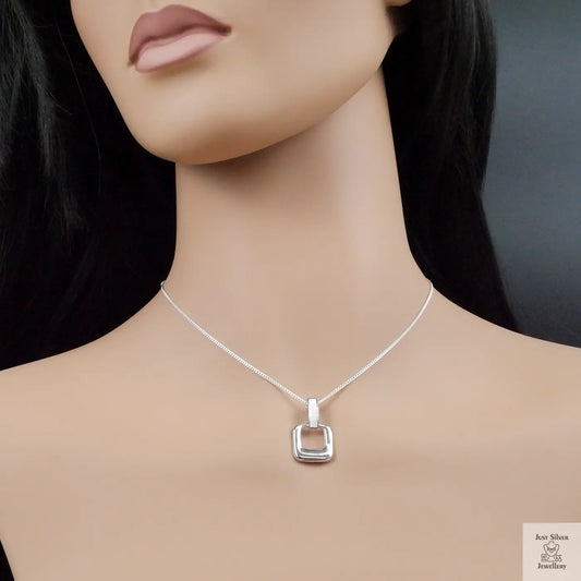 Silver necklace with a square pendant on a mannequin against a dark background