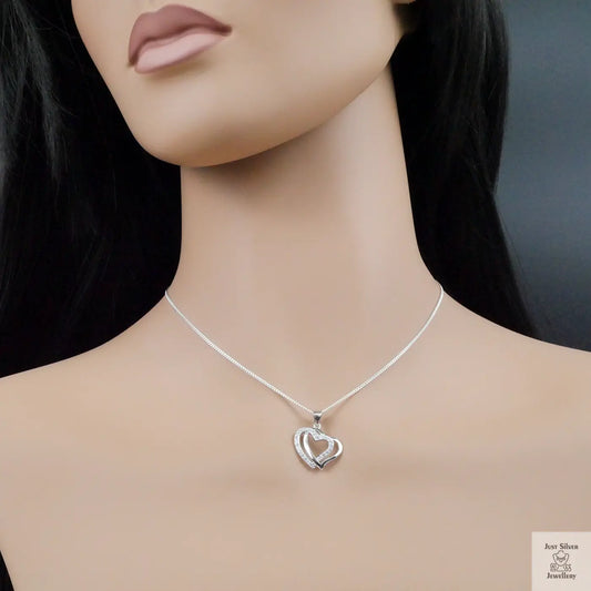 Mannequin wearing a silver necklace with a heart pendant on a dark background