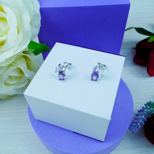 Jewelry box with a pair of earrings on a purple and white background with flowers.