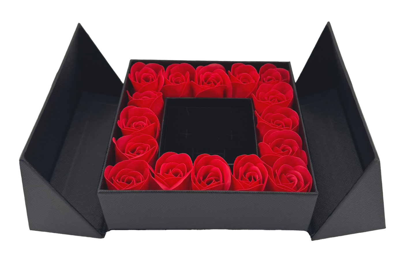A luxury gift box with a flip-top lid, containing a ring of red roses around a jewelry box with a bow on top.