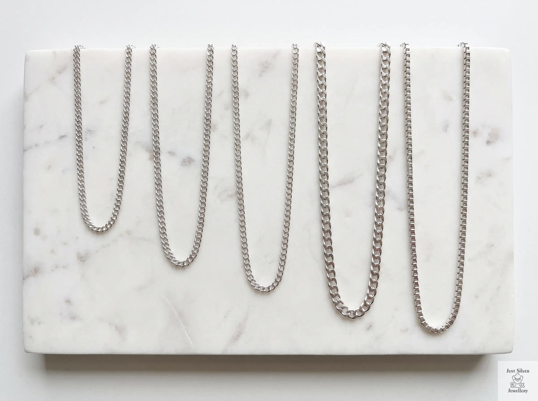 Sterling silver chain necklaces of different lengths laid out to compare choker, princess and matinee lengths