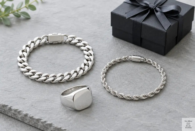 Men's sterling silver curb and rope chain bracelets and a bold silver ring beside a small gift box