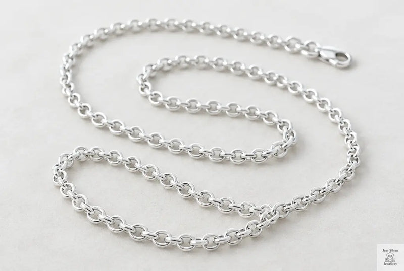 Solid sterling silver belcher chain with round, even links coiled on a white surface