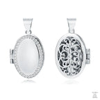 A silver oval locket with intricate designs on the front and a plain back, displayed against a white background.