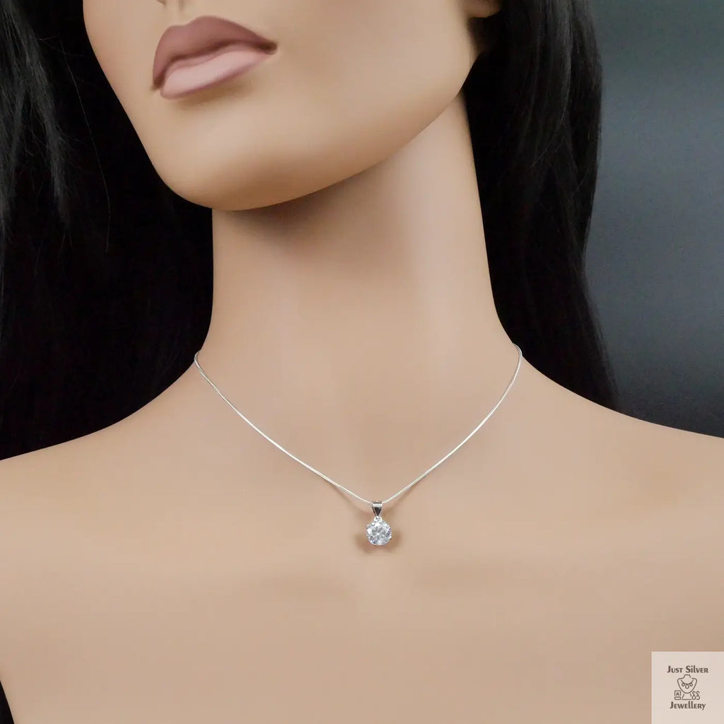 Mannequin wearing a silver necklace with a zirconia pendant on a dark background