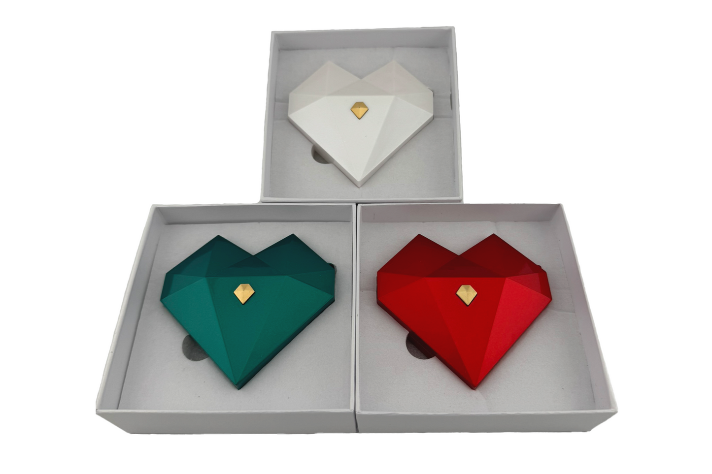 Three heart-shaped ring gift boxes in white, green, and red, with gold accents, displayed in an open presentation box.