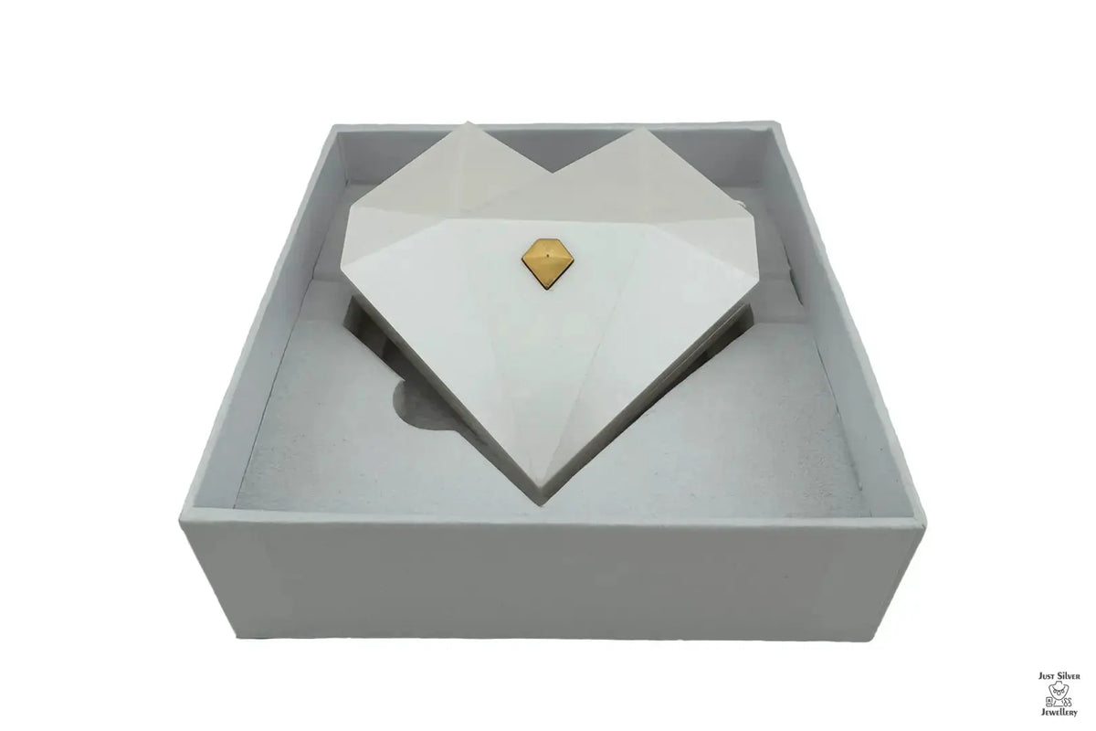 Three heart-shaped ring gift boxes in white, green, and red, with gold accents, displayed in an open presentation box.