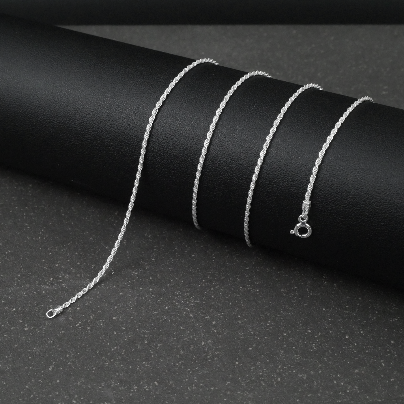 Silver rope chain necklace on a black background