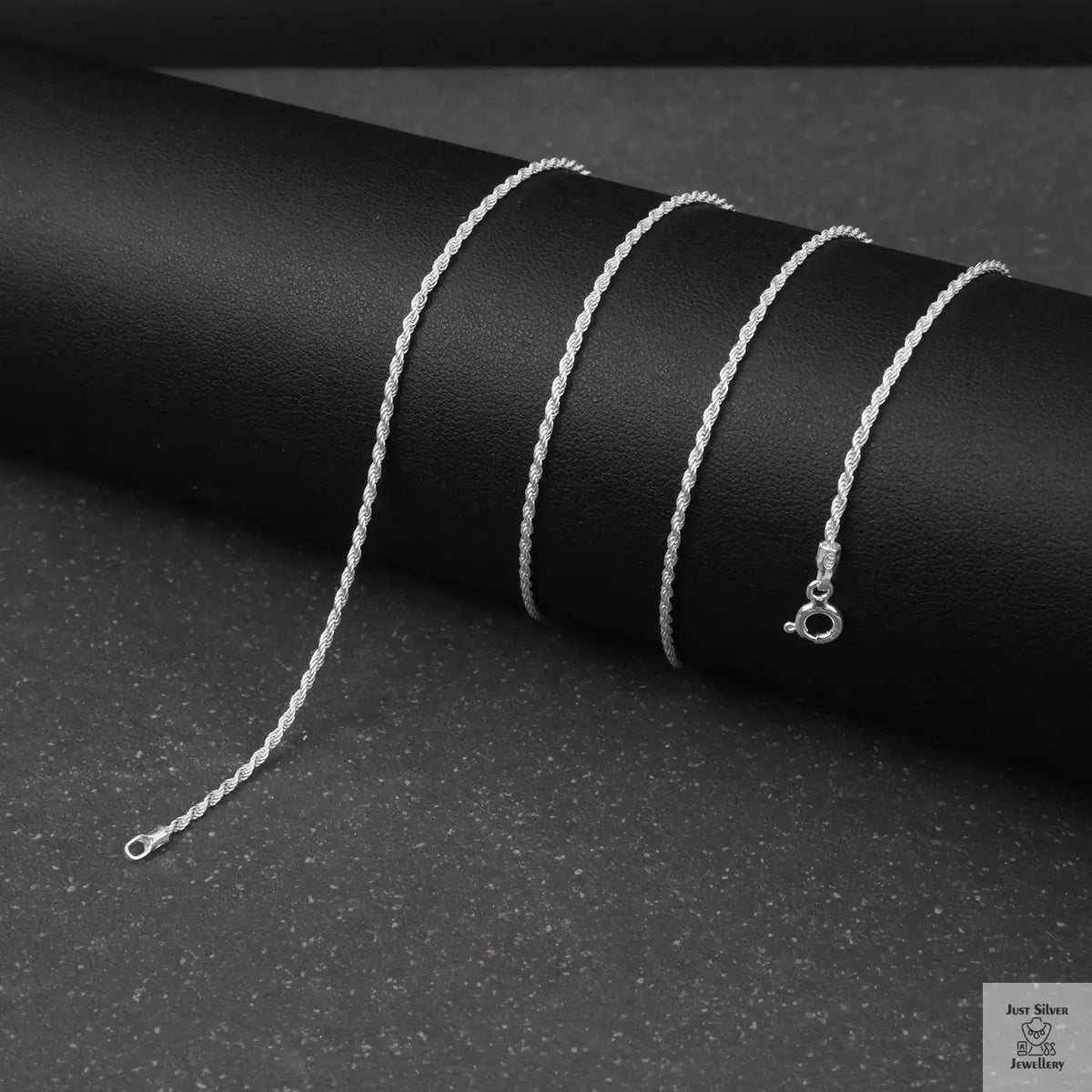 Silver rope chain necklace on a black background
