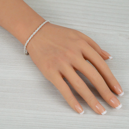 Hand wearing a silver bracelet on a light gray background