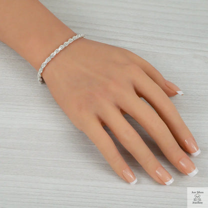 Silver bracelet on a hand with a neutral background