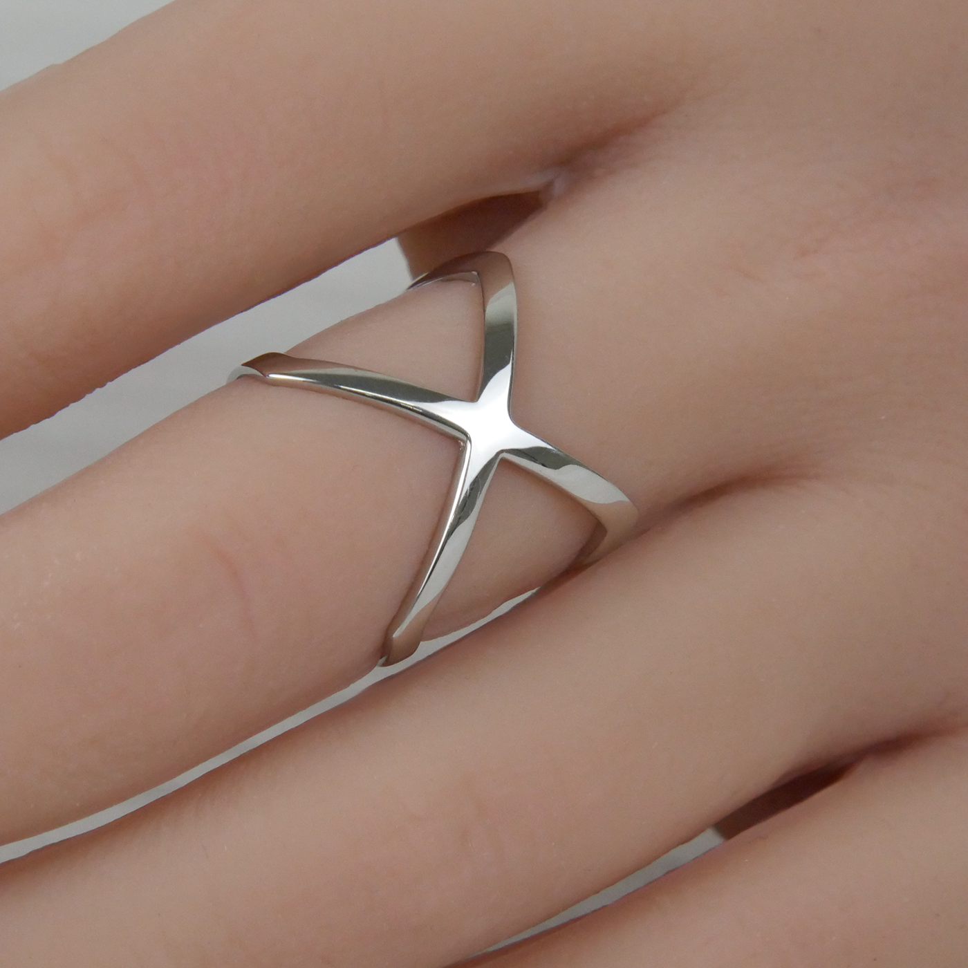 Silver ring on a finger against a neutral background