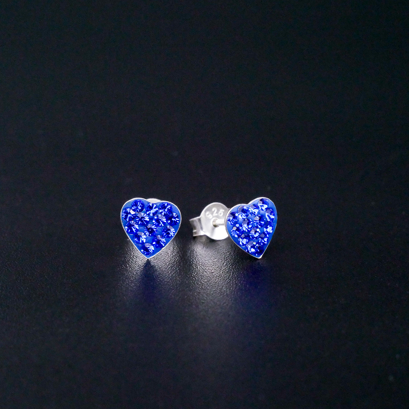 Heart-shaped blue glittery earrings on a black background