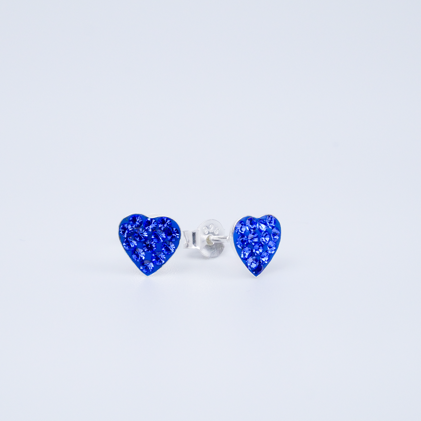 Heart-shaped blue earrings on a light grey background