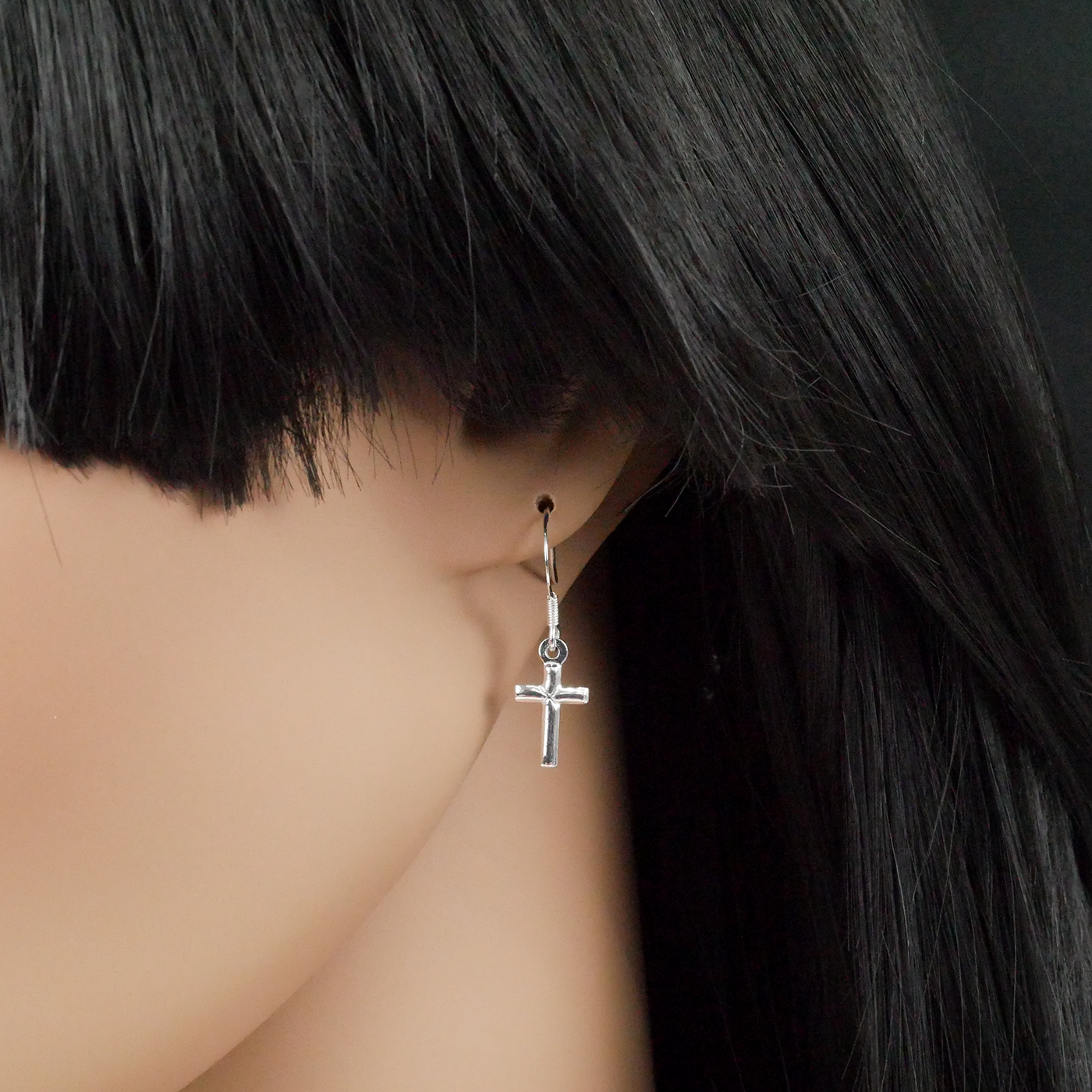 Silver cross earring on a mannequin with black hair