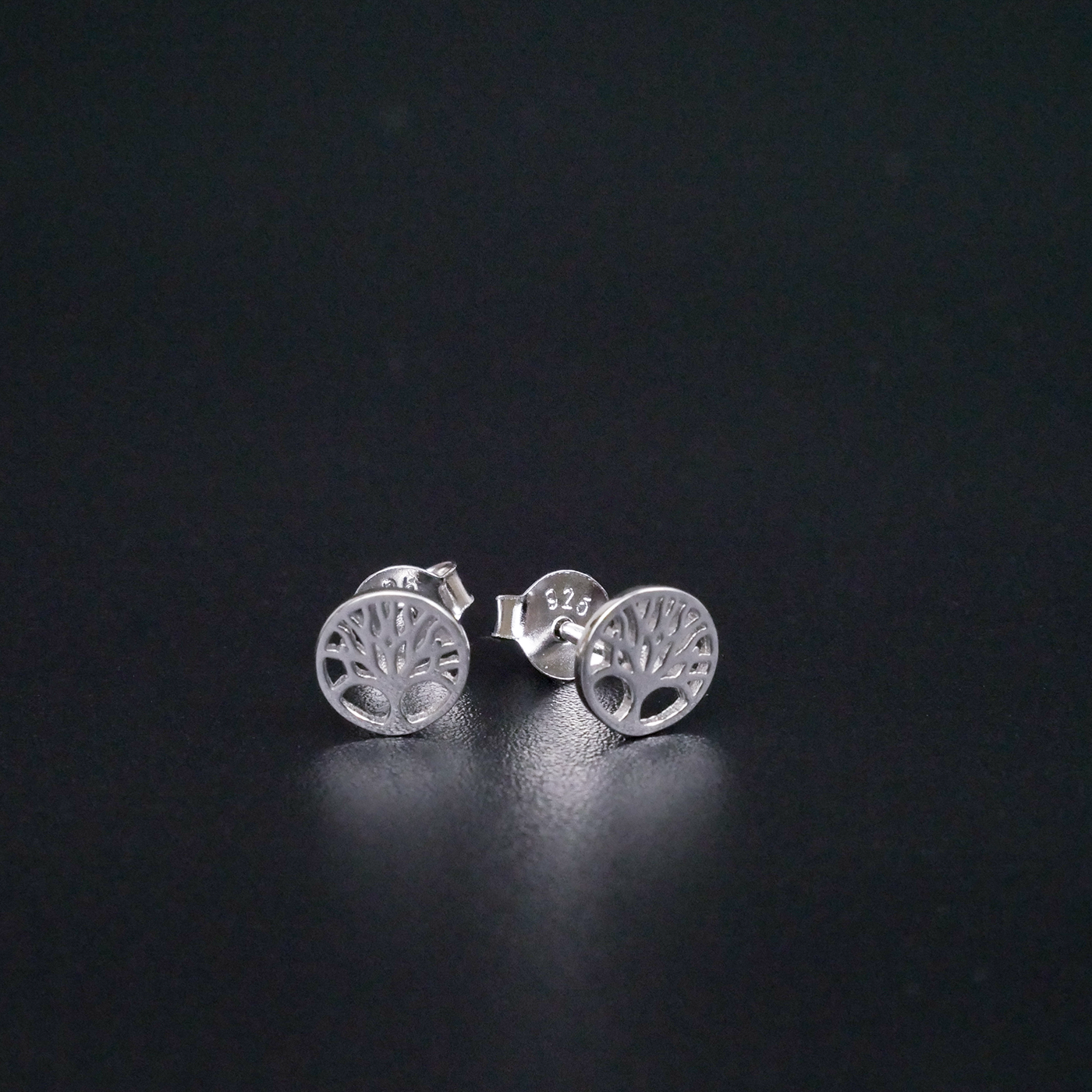 Silver tree-shaped earrings on a black background