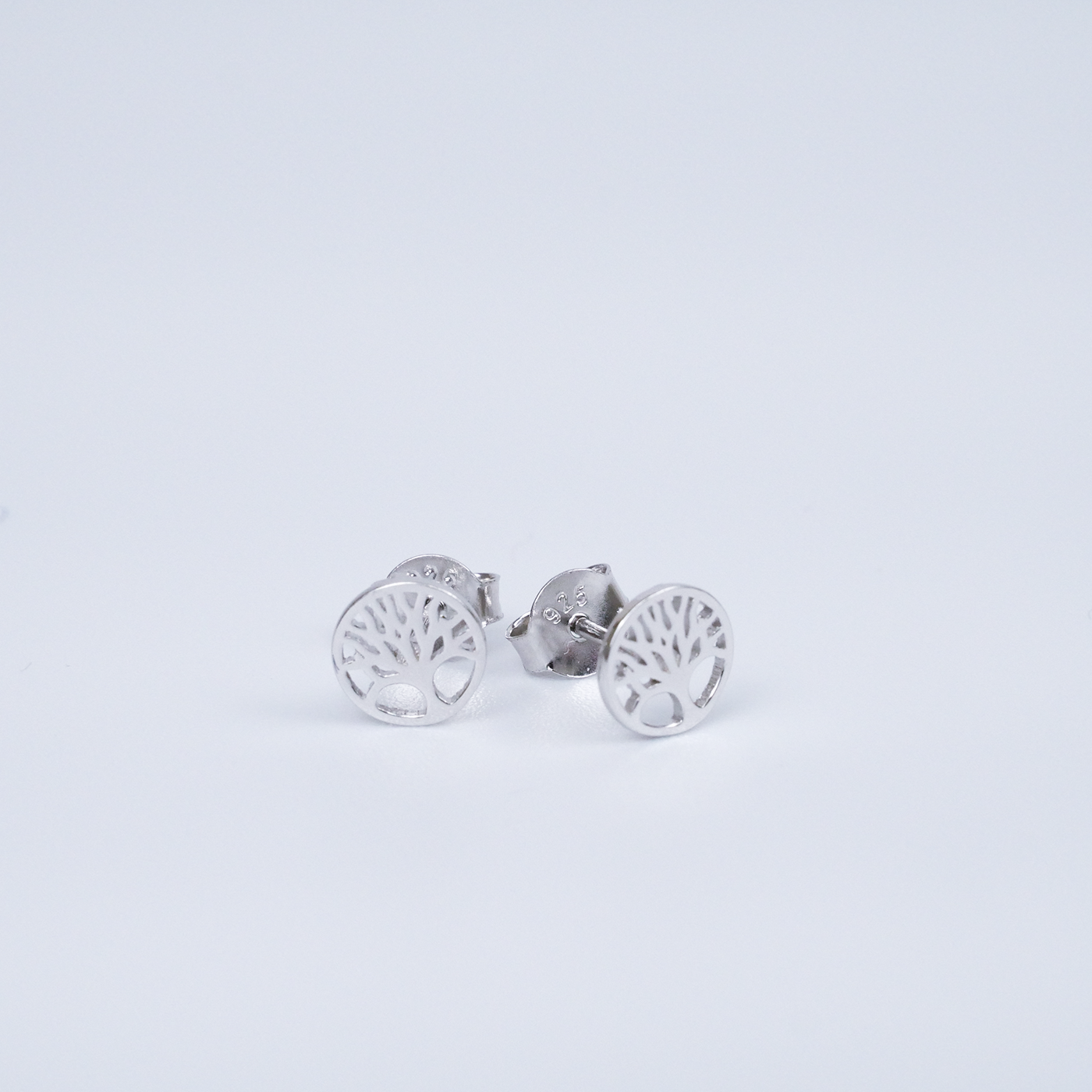 Silver tree-shaped earrings on a light gray background