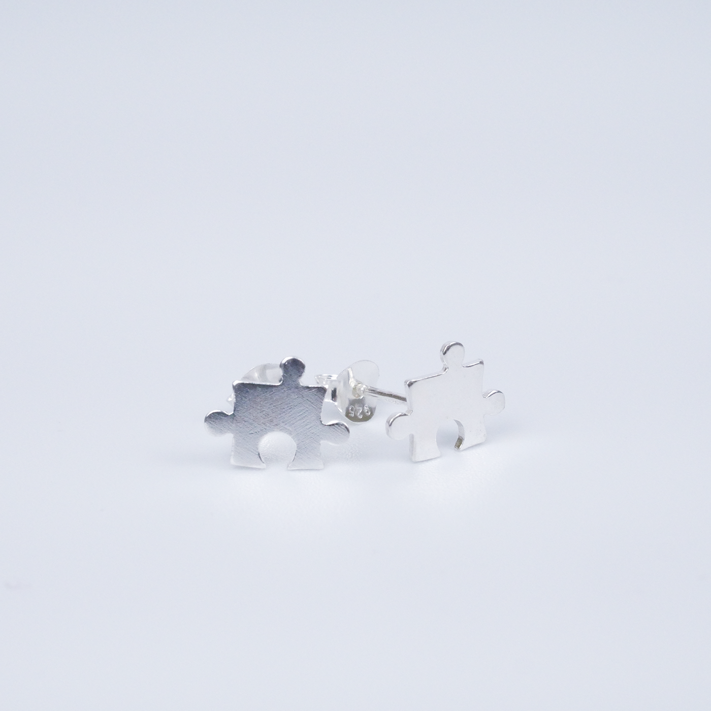 Silver puzzle piece earrings on a light gray background