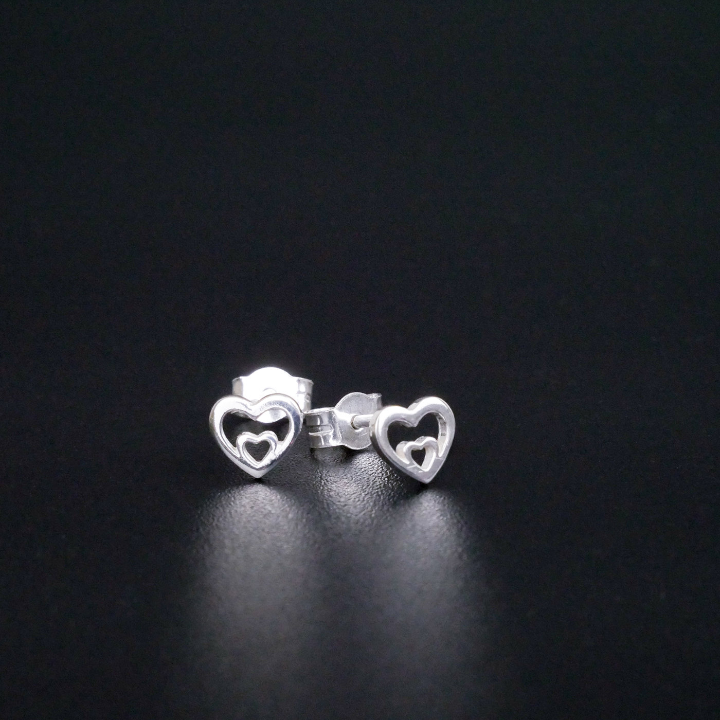 Silver heart-shaped earrings on a black background