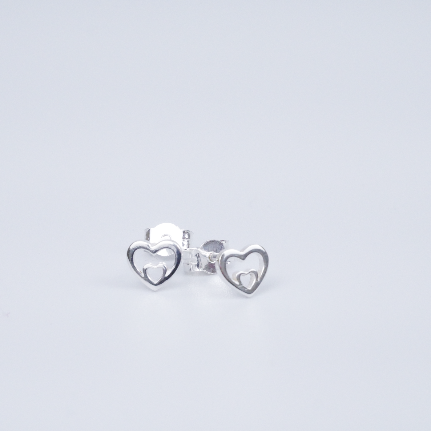 Silver heart-shaped earrings on a light grey background