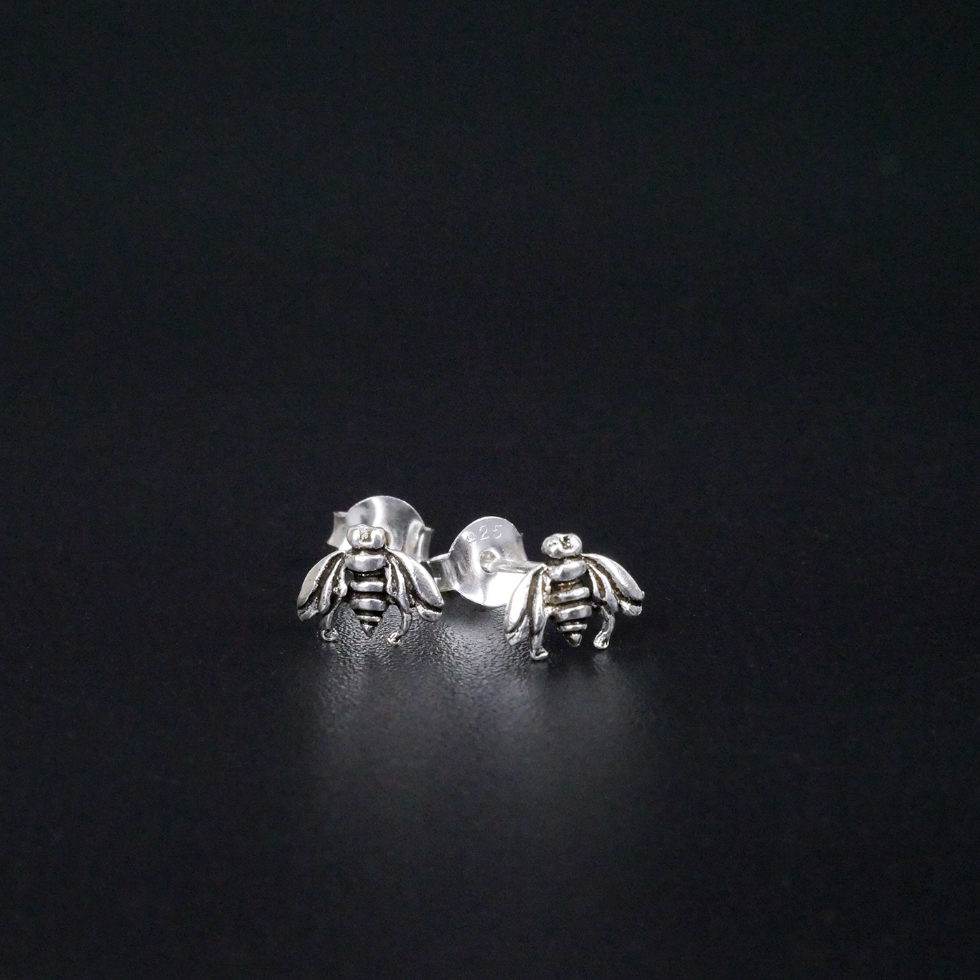 Silver bee earrings on a black background