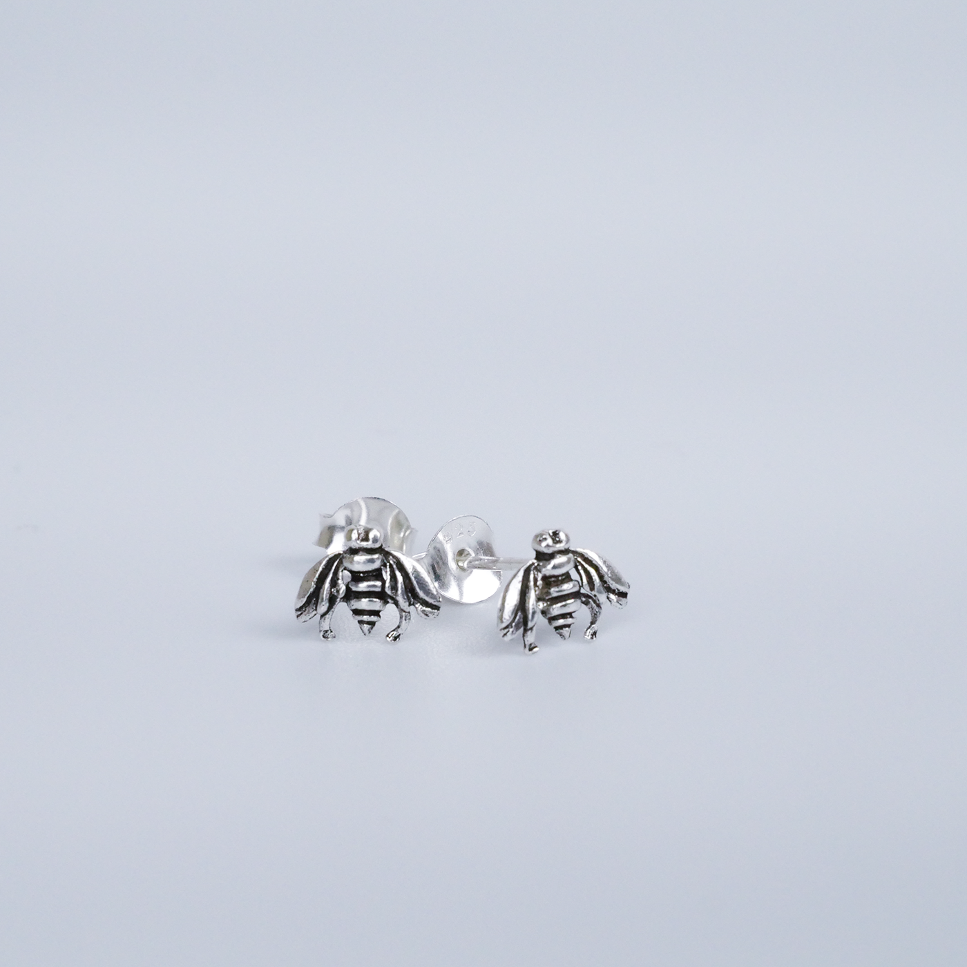 Silver bee-shaped earrings on a light gray background