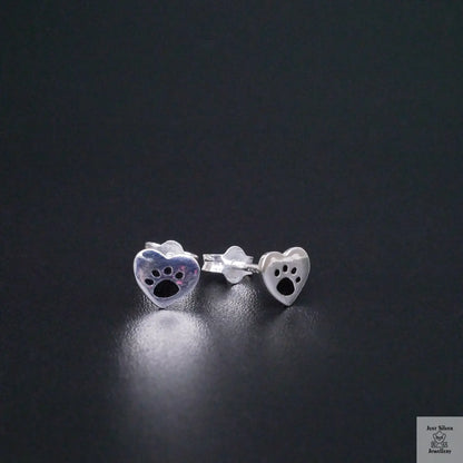 Silver paw print earrings on a black background