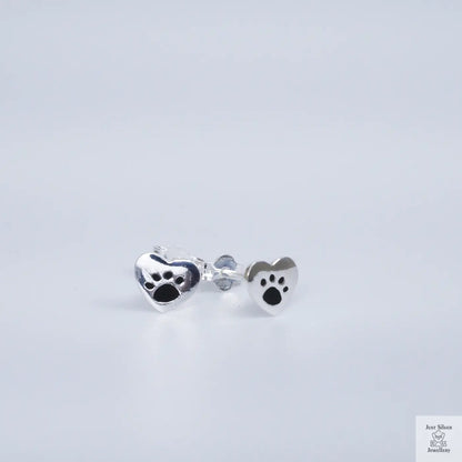 Silver paw print earrings on a light gray background