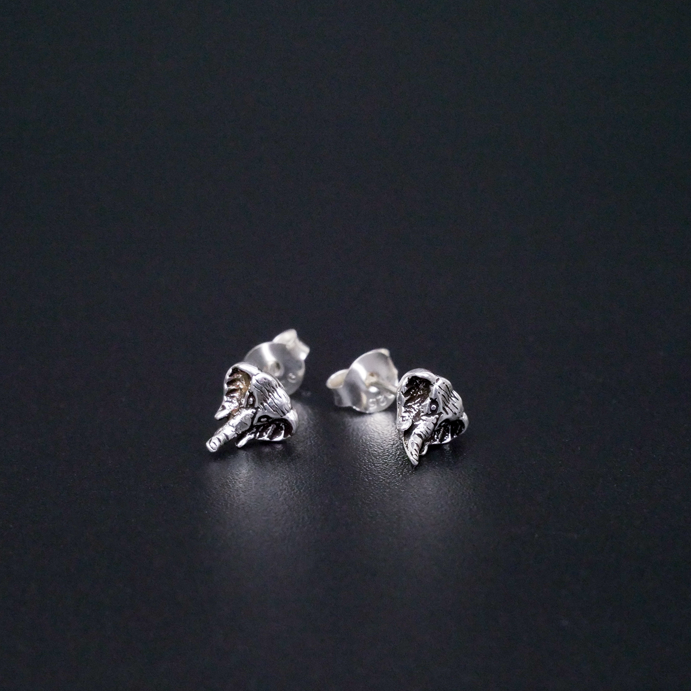 Silver elephant earrings on a black background