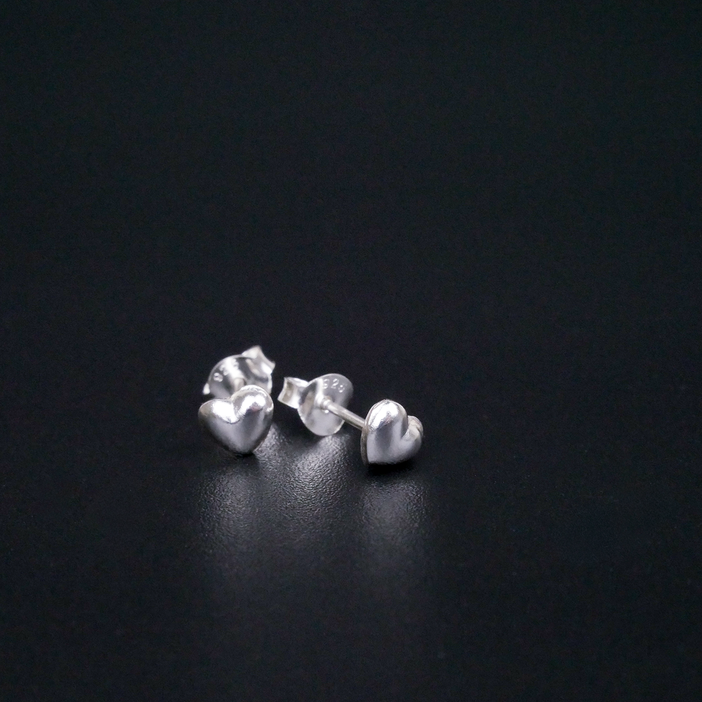 Heart-shaped silver earrings on a black background