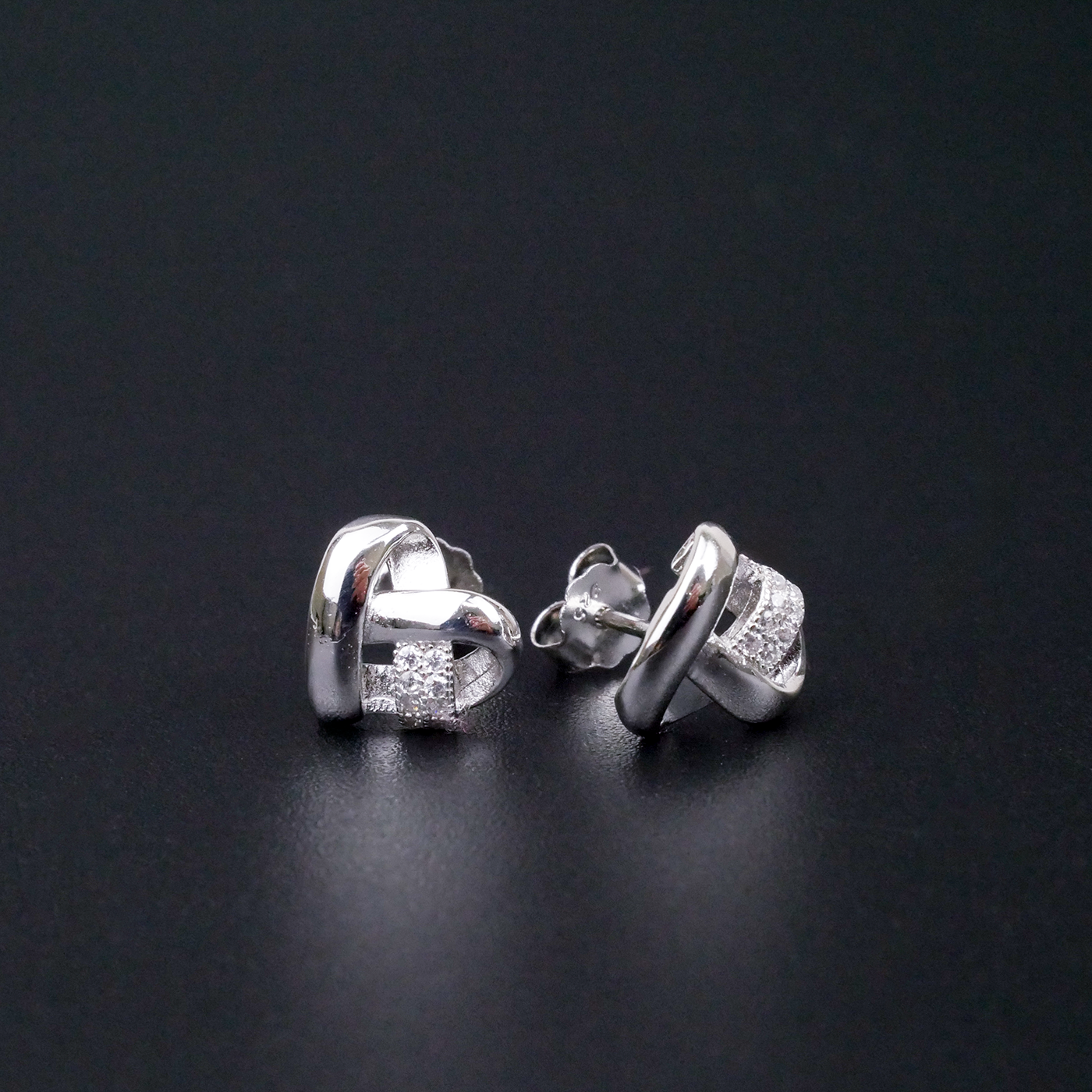Pair of silver earrings with clear stones on a black background
