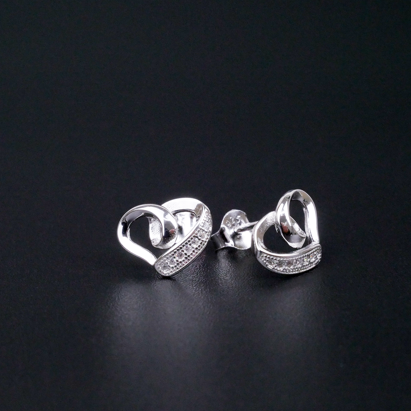 Silver heart-shaped earrings on a black background