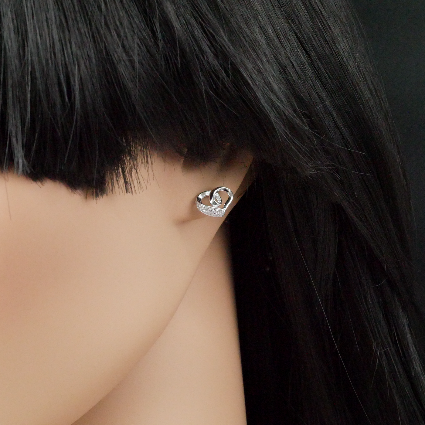 Silver heart-shaped earring worn by a person with black hair.