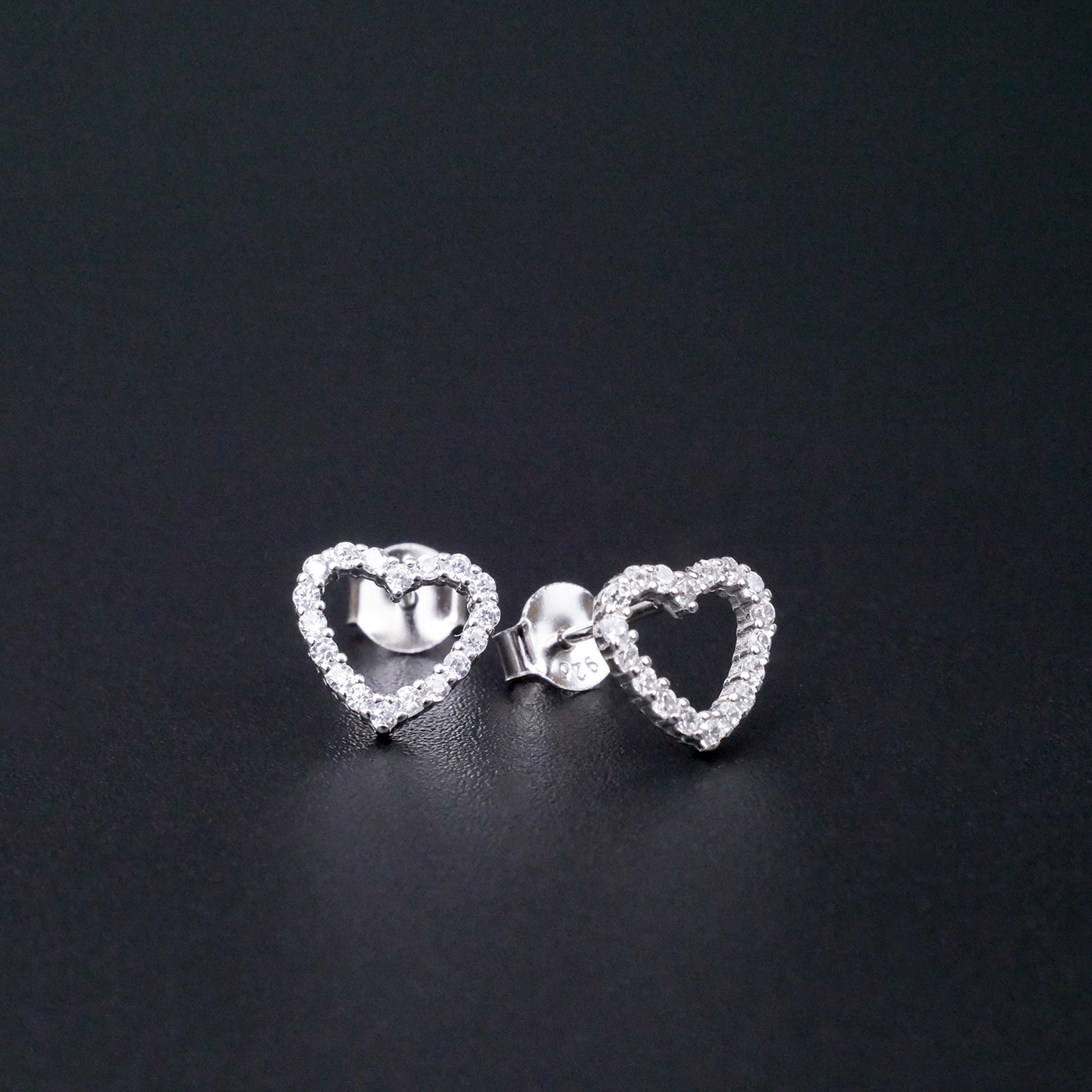 Heart-shaped earrings with clear stones on a black background