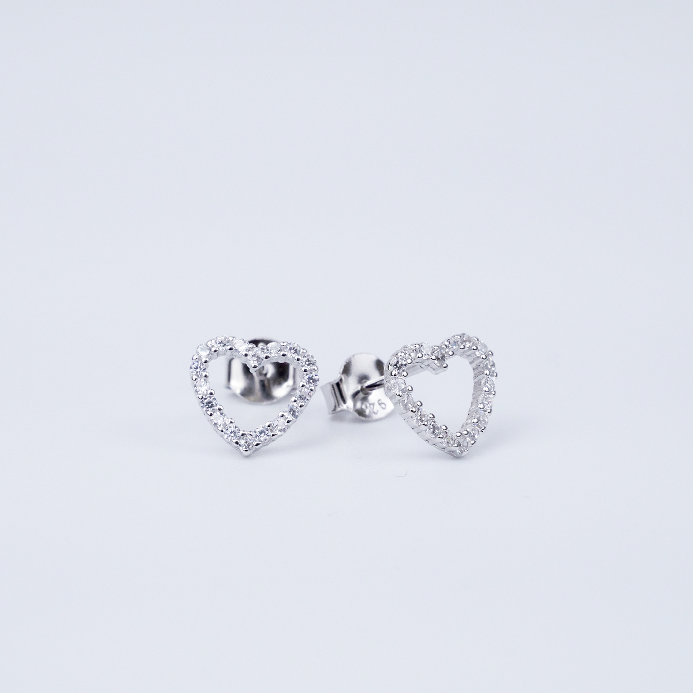 Heart-shaped silver earrings on a light gray background
