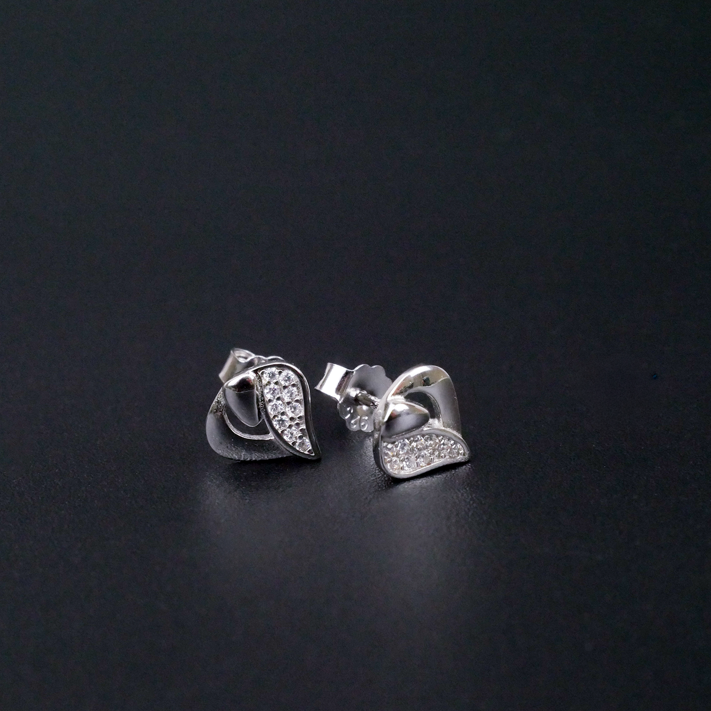 Silver earrings with leaf design on a black background