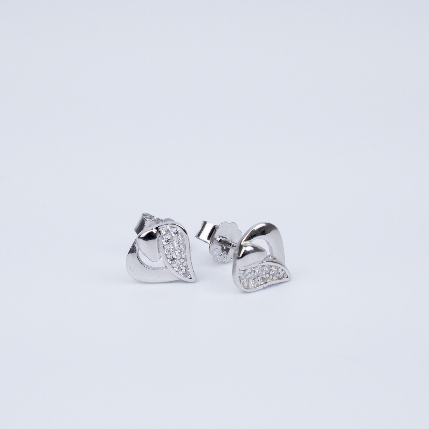 Pair of silver earrings with heart design on a light gray background