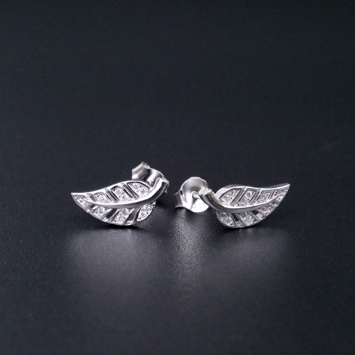 Silver leaf-shaped earrings on a black background