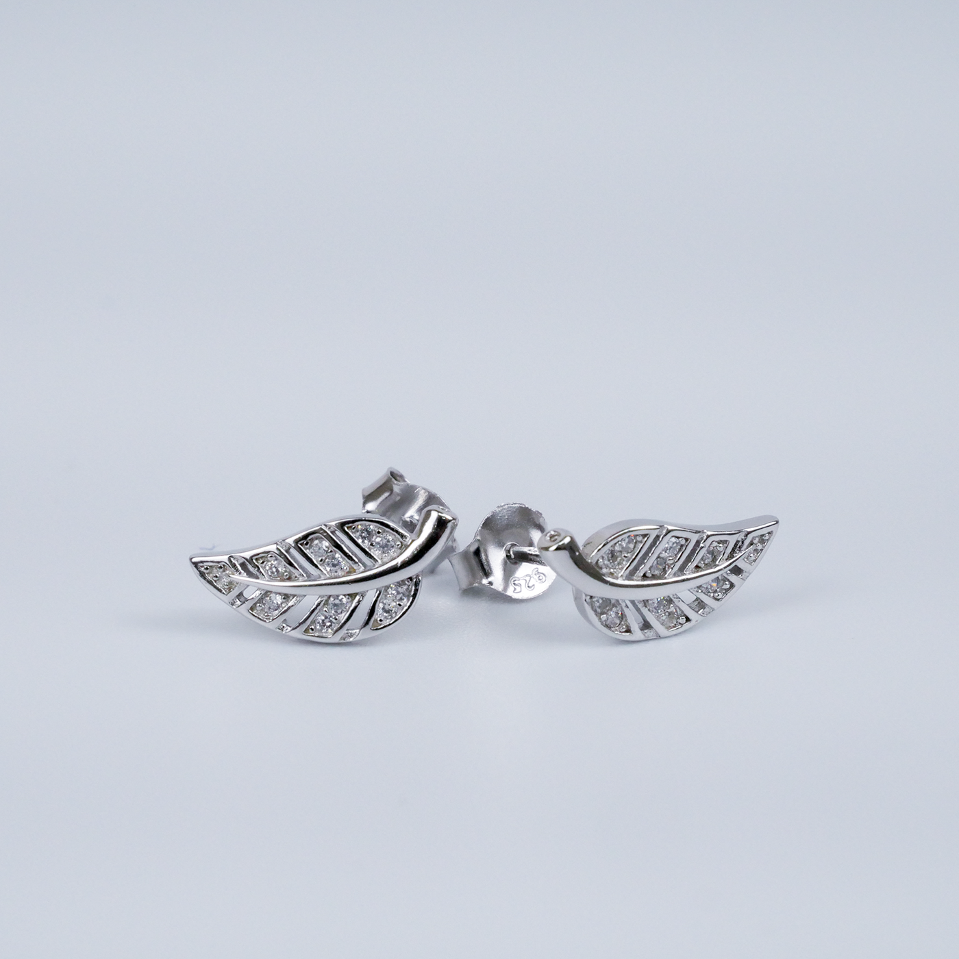 Silver leaf-shaped earrings on a light gray background