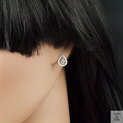 Teardrop-shaped silver earring worn by a person with dark hair.