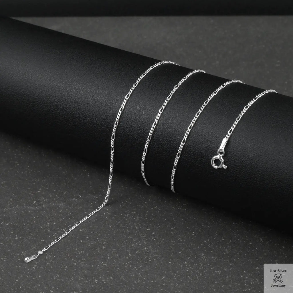 Silver fine figaro chain necklace on a black surface