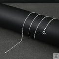 Silver fine figaro chain necklace on a black surface