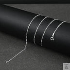 Silver fine figaro chain necklace on a black surface
