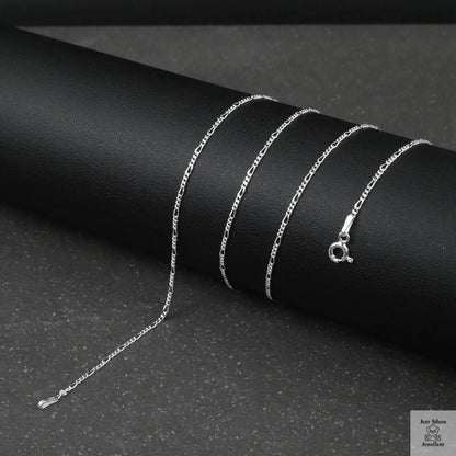 Silver fine figaro chain necklace on a black surface