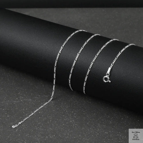 Silver fine figaro chain necklace on a black surface