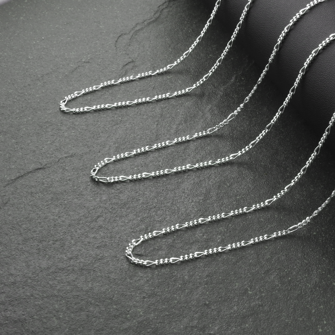 Silver chain necklace on a dark gray surface