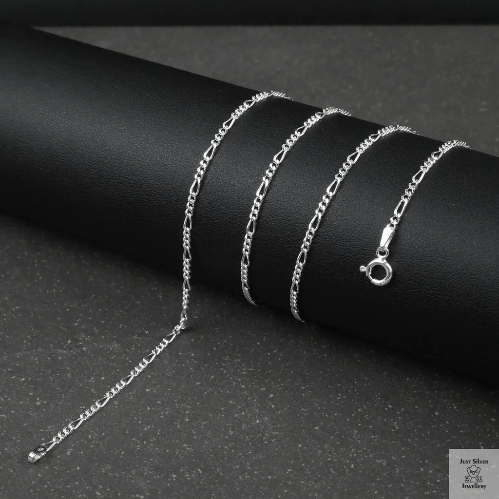 Silver fine figaro chain necklace on a dark surface